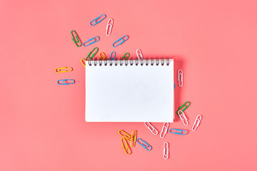Blank paper notebook near stationery items on pink desk