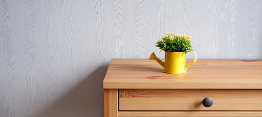 Beautiful design of a wooden table and watering can with a bouquet of flowers on the background of a blue wall. Advertising background.