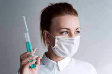 Portrait of a girl in a medical mask. Holding a syringe in her hand. Close up..