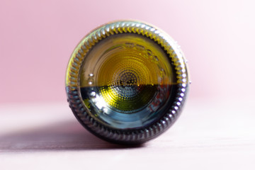 Bottom of green bottle with half of red wine on brown background