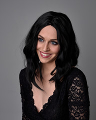 Close up portrait of a pretty, goth girl with dark hair  posing in front  a studio background.