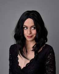 Fototapeta premium Close up portrait of a pretty, goth girl with dark hair posing in front a studio background.