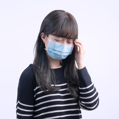 Young woman is feeling dizzy, headache, sick, unwell with wearing a medical blue face mask over the...