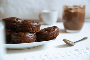 Home made chocolate muffins served on a rustic kitchen next to some cups with coffee and tea. Empty copy space for Editor's text.