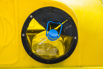 A yellow bottle bank for recycling plastic and glass bottles. The large opening hole to insert into.