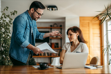 Fototapeta premium Dissatisfied executive talking to an employee about work mistake. Couple having a fight over documents at home, portrait.
