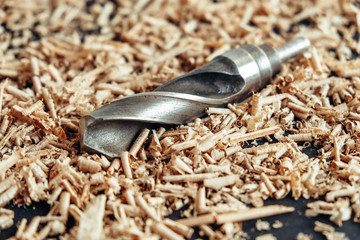 Wood drill bit with wooden shavings on black background. Copy, empty space for text