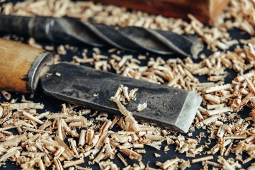 Old hand plane, drill and chisel with wooden shavings on black background. Old woodworking hand tool. Copy, empty space for text