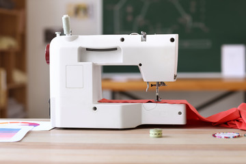 Modern sewing machine on table in tailor's workshop