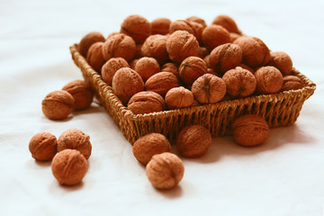 Walnuts on the rough in a wicker basket on a white background. Close-up. Copy space
