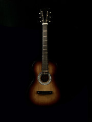 Six-stringed acoustic guitar on a black background. Musical string instrument. Guitar fretboard.