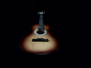 Six-stringed acoustic guitar on a black background. Musical string instrument. Guitar fretboard.
