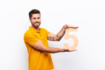 young handsome man excited, happy, joyful, holding a number 5.