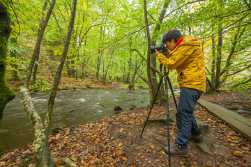 Obraz premium A photographer takes pictures of a beautiful view of the river and forest, selective focus, long exposure
