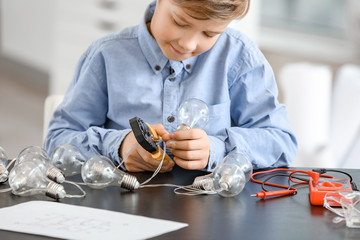 Cute little electrician performing wiring at table