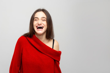 Portrait of a young woman with bright positive emotions on a light gray background. Photo laughs girls.