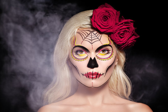Beautiful Halloween Make-Up. Blond Model Wear Sugar Skull Makeup with Red Roses. Day of the Dead or Santa Muerte concept