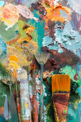 various brushes for oil paints are on the palette. set for the artist. multicolored background