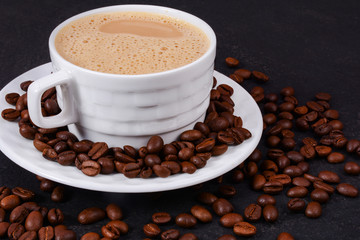 A cup of hot coffee and coffee beans on a black background