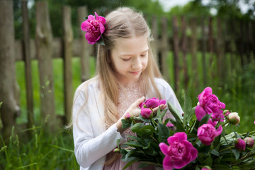 Beautiful little blonde girl with metal bucket with peonies