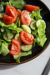Summer fresh detox salad with tomatoes, cucumber, romaine lettuce and olive oil on grey concrete background. Healthy diet food for vegan or vegetarian, top view