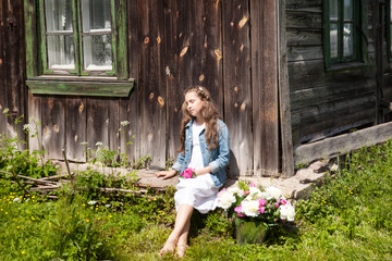 Beautiful little brunette girl with metal bucket with peonies