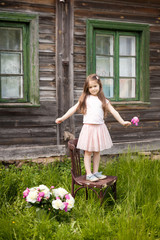 Beautiful little brunette girl near old wooden house