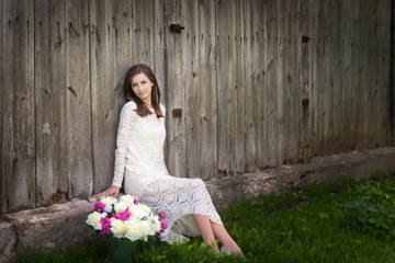 Beautiful young woman in a cream dress with peonies