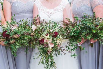 Bride and bridesmaids holding the wedding bouquet, with beautiful flowers