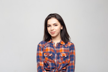 Portrait young beautiful woman not smiling in plaid shirt isolated on white-gray background. Girl...