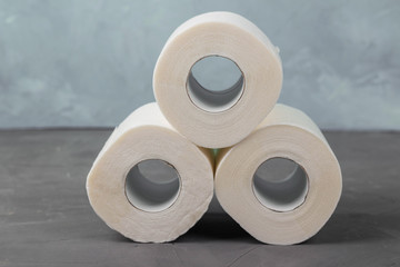 Pyramid of three toilet paper rolls on a gray background