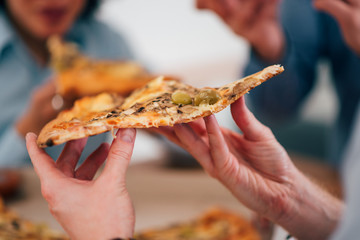 Eating pizza with friends, close-up.