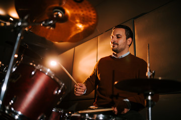 Naklejka premium Low angle image of a drummer playing indoors.