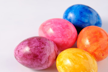 Five naturally looking coloured Easter eggs lying isolated on white background with copy space.