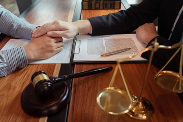 Lawyer working with client discussing contract papers with brass scale about legal legislation in courtroom, consulting to help their customer.