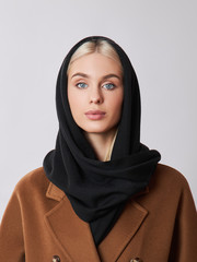 European Muslim woman with a blonde hair in a headscarf shawl dressed on her head. Beautiful girl in coat with soft skin, natural cosmetics