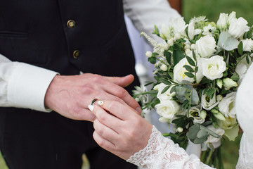 beautiful girl bride in wedding white dress puts on the groom's finger the wedding gold ring.