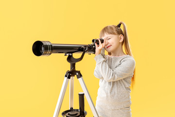 Cute little girl with telescope on color background