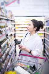 Asian beautiful woman using smart phone shopping in super market