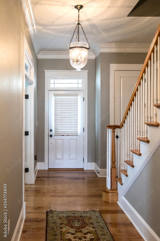 Wall mural view of a white front door entrance in a new construction house with a hanging chandelier clear glas