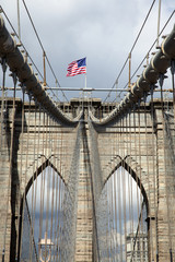 Obraz premium Architectural detail of the Brooklyn Bridge on which the American flag is flying