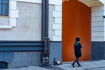  girl walking a dog in an urban environment.  dog on a leash