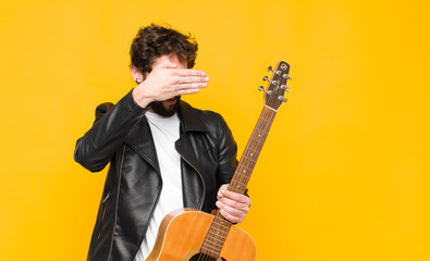 young musician man covering face with both hands saying no to the camera! refusing pictures or...