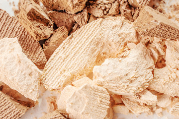 Eyeshadows of neutral beige and brown shades are scattered on a light surface. Detailed macro photo. The concept of decorative cosmetics.