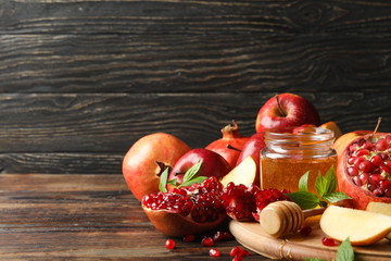 Apples, pomegranate and honey on wooden background, space for text