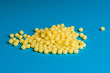 Yellow medical pills on blue background with copy space for text. Alternative homeopathy medicine, healthcare and wellness concept.