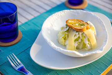 Gourmet salad with camembert cheese and toast on top. Elegant restaurant outdoor table
