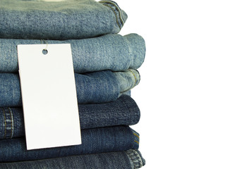 A stack of new jeans with white paper tag mockup and copy space isolated on white