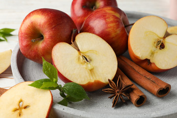Tray with apple and cinnamon, and towel on wooden background, close up