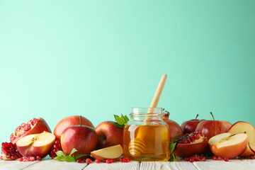 Apples, pomegranate and honey against mint background, space for text